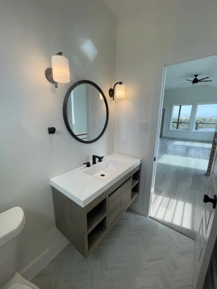 Spacious bedroom with light wood flooring, large windows bringing in natural coastal light, and neutral wall tones complementing the contemporary design