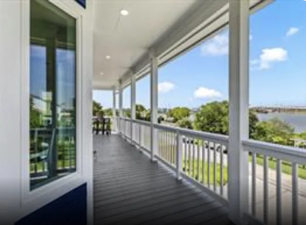 Covered porch running the full length of the 5th St Seabrook cottage, with white railing and views across the bay