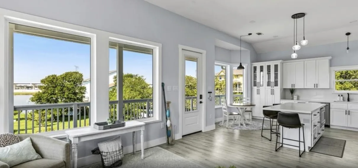 Open living and kitchen area at 5th St Seabrook with a wall of windows framing the bay view