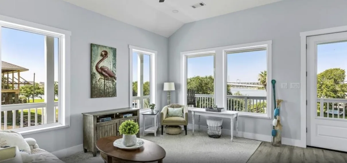 Living room at 5th St Seabrook with coastal artwork, built-in window seating, and doors to the porch