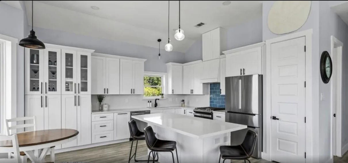 White kitchen at 5th St Seabrook with shaker cabinetry, quartz counters, pendant lighting, and a dining table
