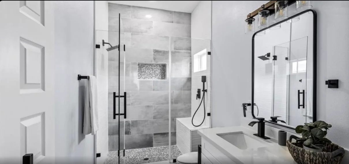Bathroom at 5th St Seabrook with a double vanity, black-framed mirrors, and a glass-enclosed tile shower