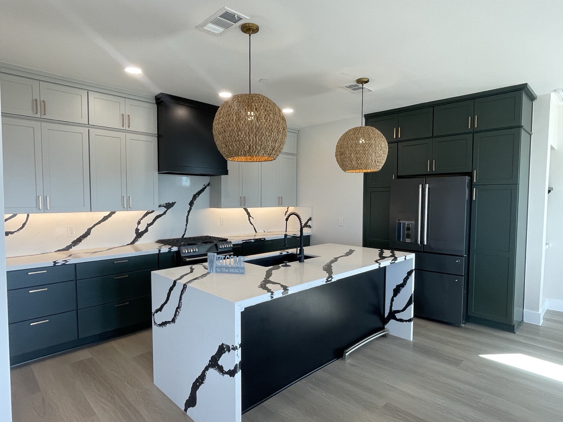 Primary bathroom vanity with custom cabinetry, designer mirror, and gold fixtures against bold tile accent wall in the Blue Heron home