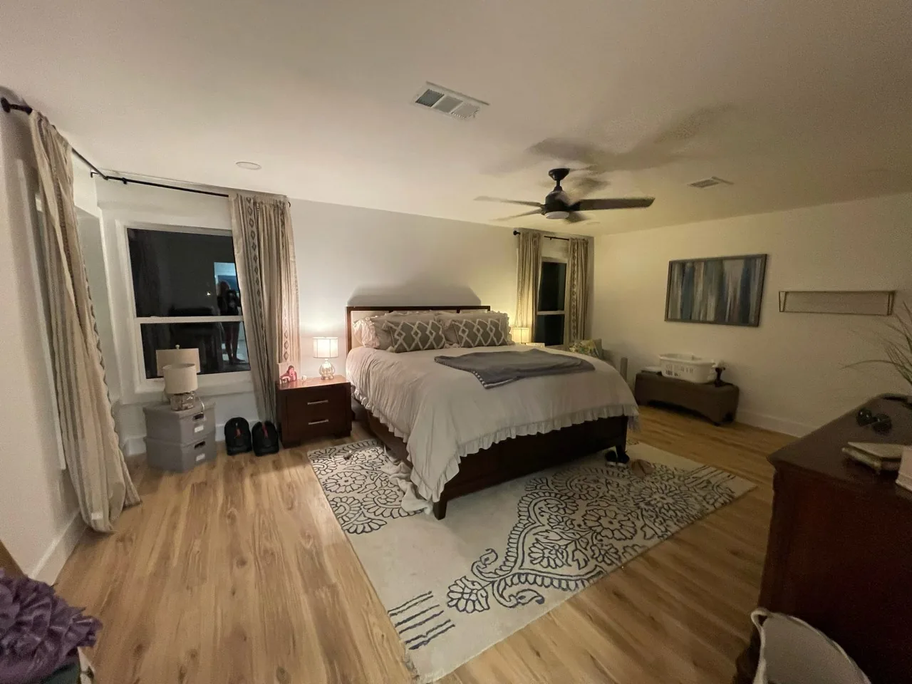 After: renovated primary bedroom at the Flounder house with wood-look flooring and a wall-mounted television