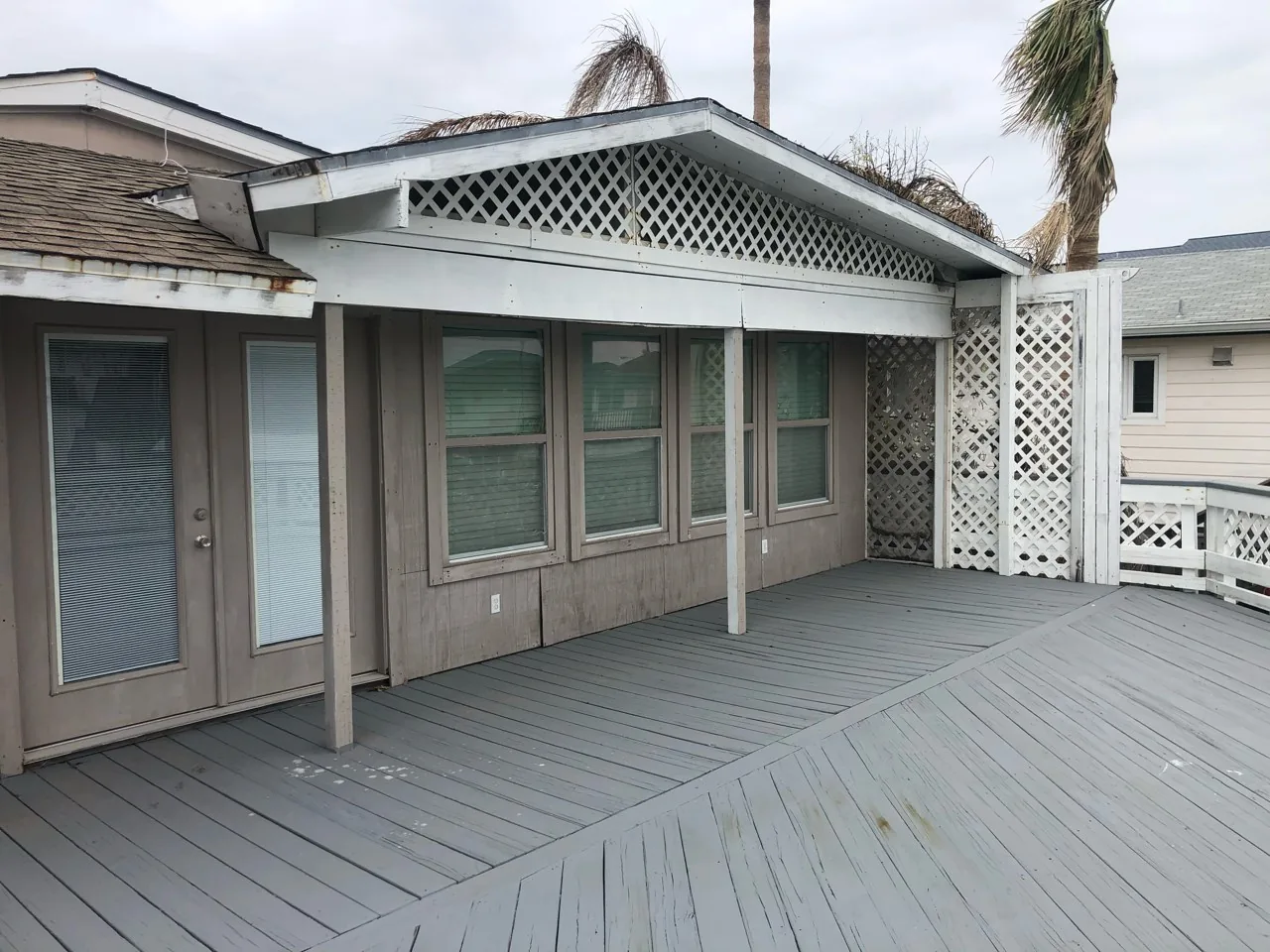 Before: original rear deck at the Flounder house with weathered decking, lattice screening, and dated posts