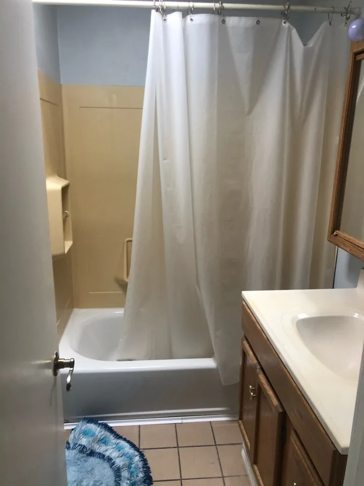 Before: original hall bath with a tub-shower combination, curtain rod, and dated vanity