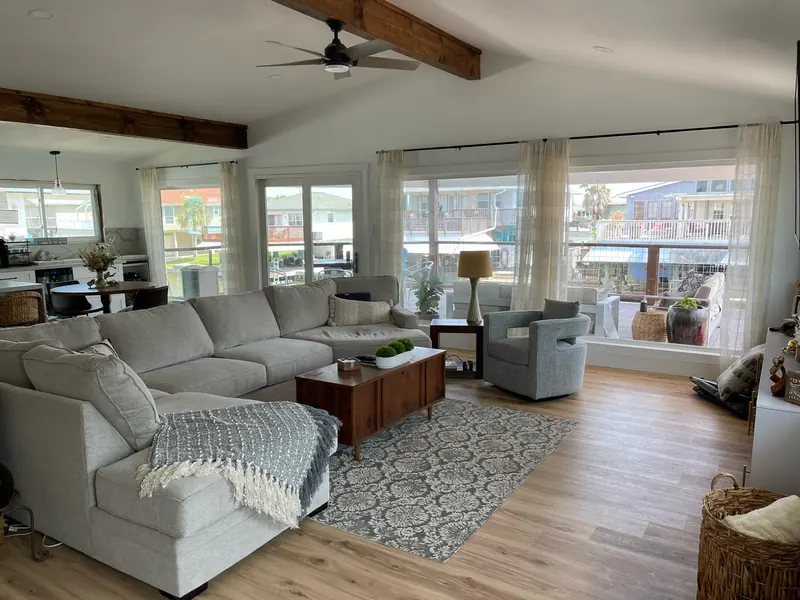 After: living area at the Flounder renovation with a deep sectional, layered rug, and windows on the canal side