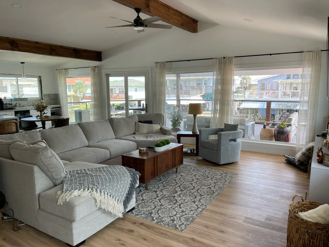 After: living area at the Flounder renovation with a deep sectional, layered rug, and windows on the canal side