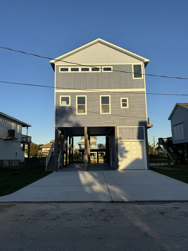 Front elevation of the Galleon custom home in Jamaica Beach, Galveston, raised on pilings with a concrete drive running under the structure