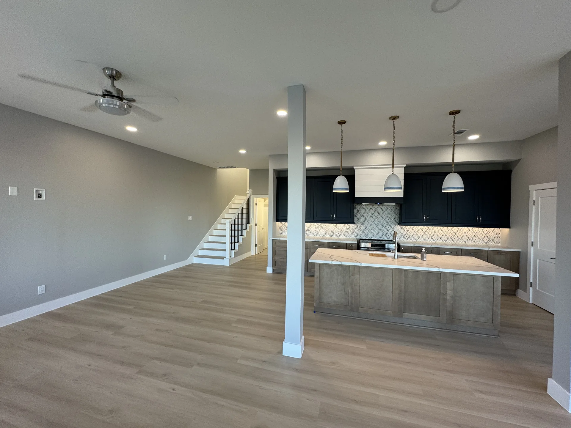 Great room at Galleon looking back toward the kitchen and stair, with the ceiling fan and recessed lighting