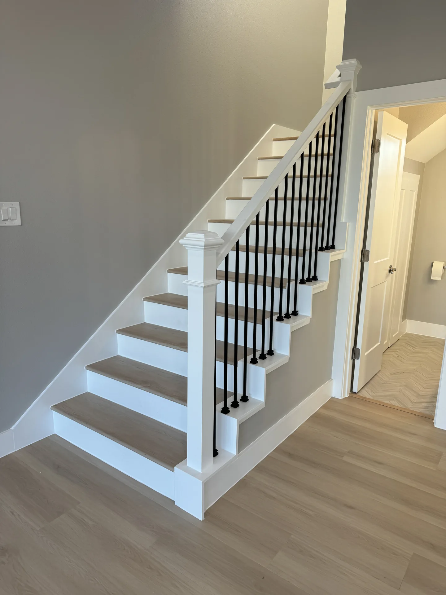 Staircase at Galleon with white risers, wood treads, and black iron balusters connecting the living levels