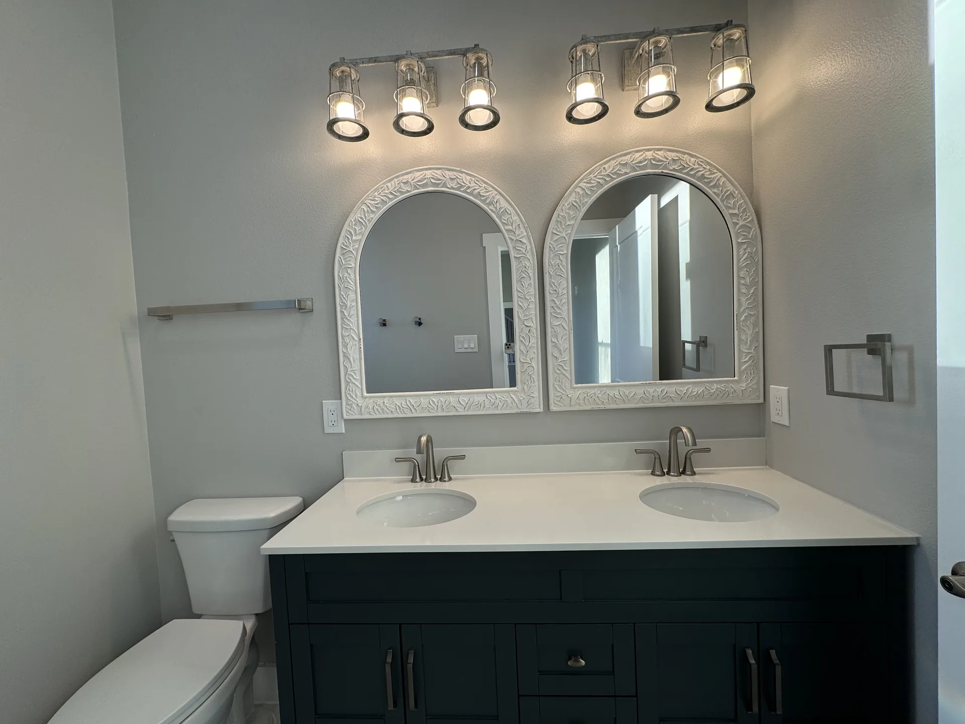 Galleon double vanity with white quartz counter, navy shaker cabinets, and brushed nickel sconce lighting