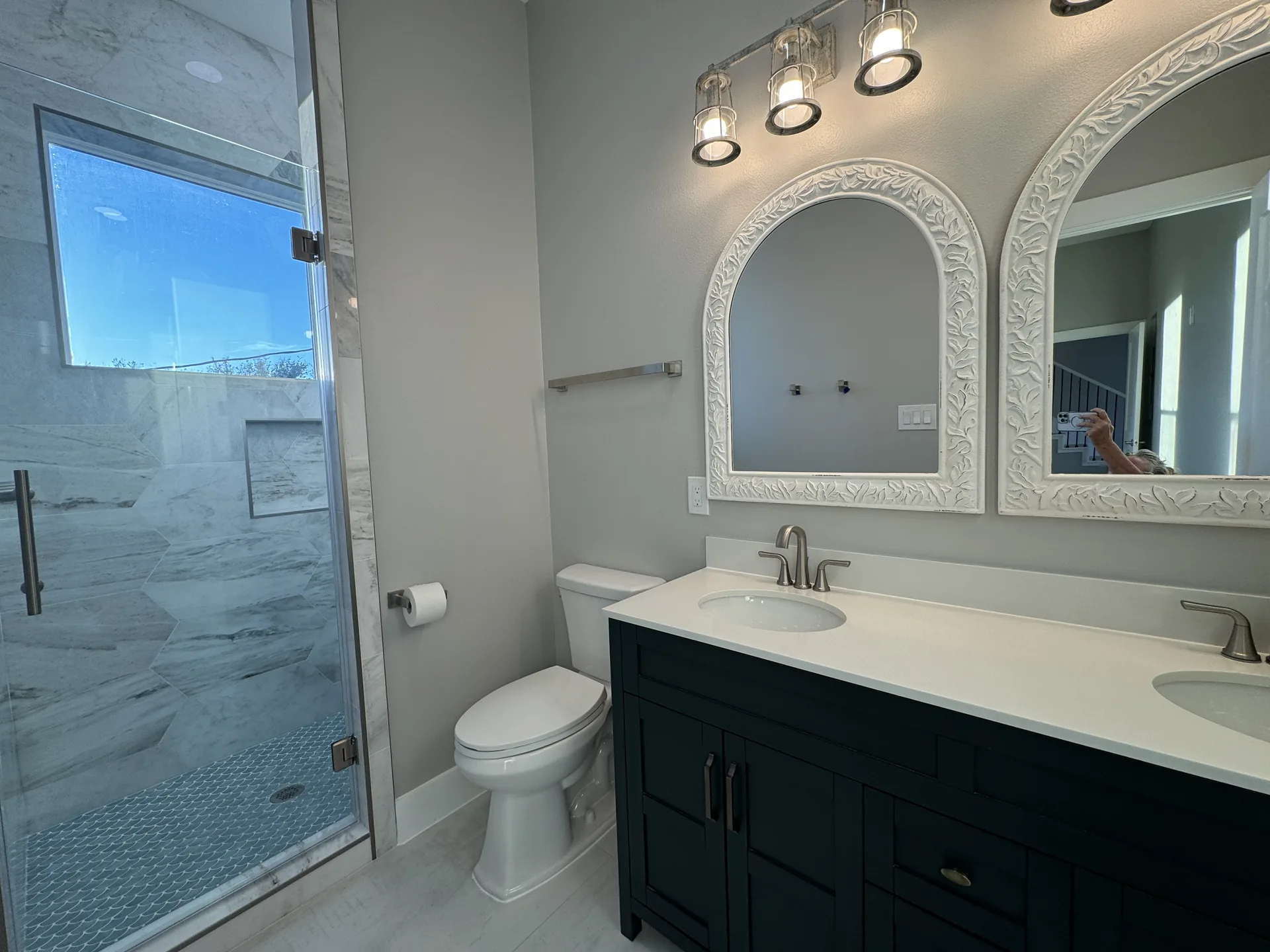 Full bath at Galleon pairing the double vanity with a walk-in glass shower and marble-look wall tile