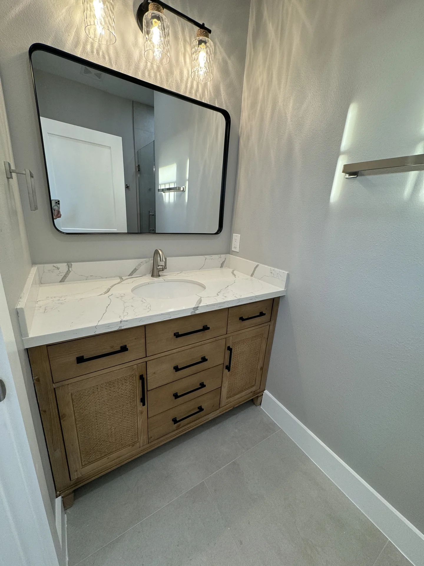 Double wood vanity at Galleon with quartz counters, black mirrors, and a wall-mounted towel bar