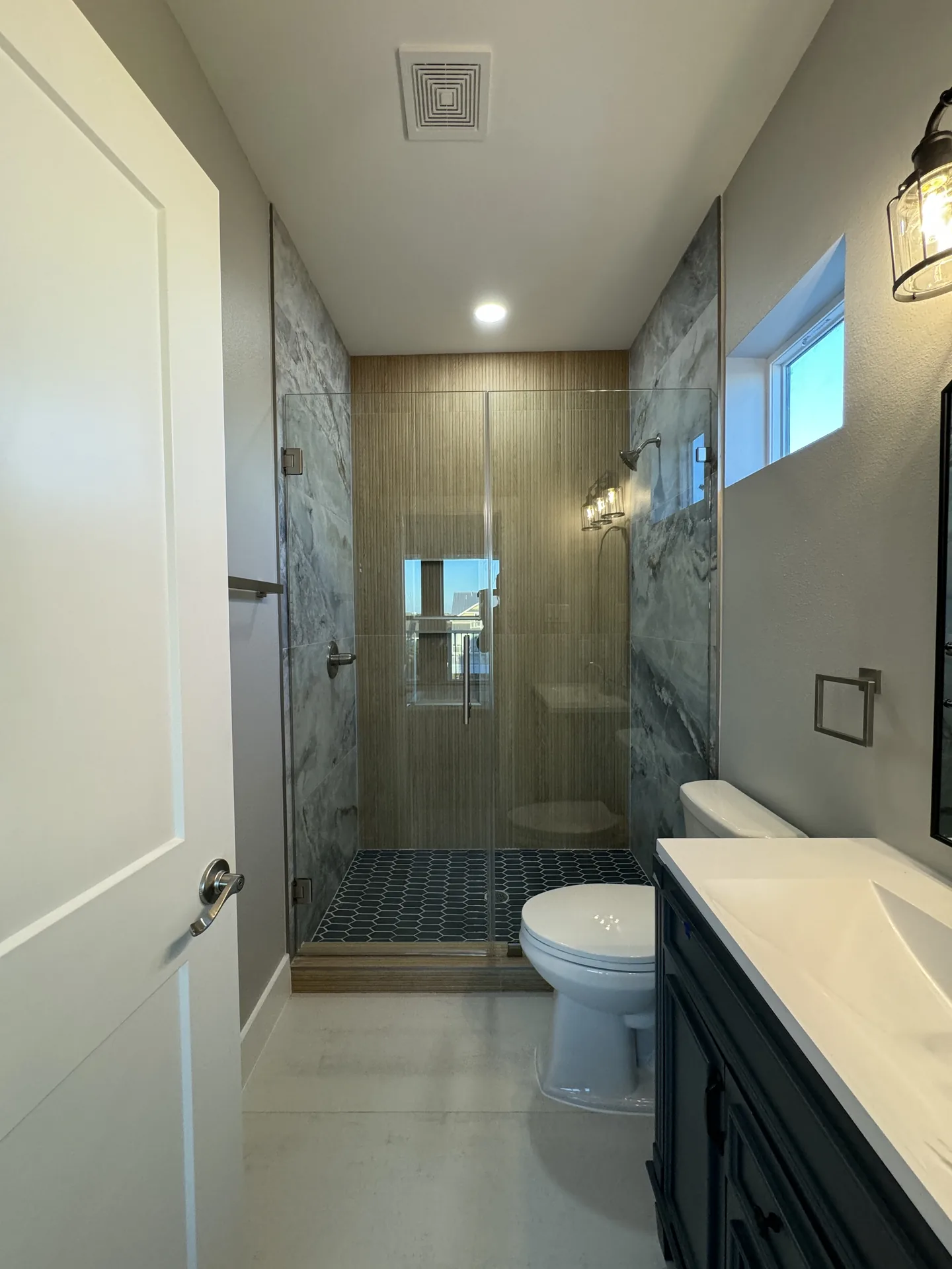 Long view through a Galleon bathroom toward the glass shower, showing the vanity run and tile detail