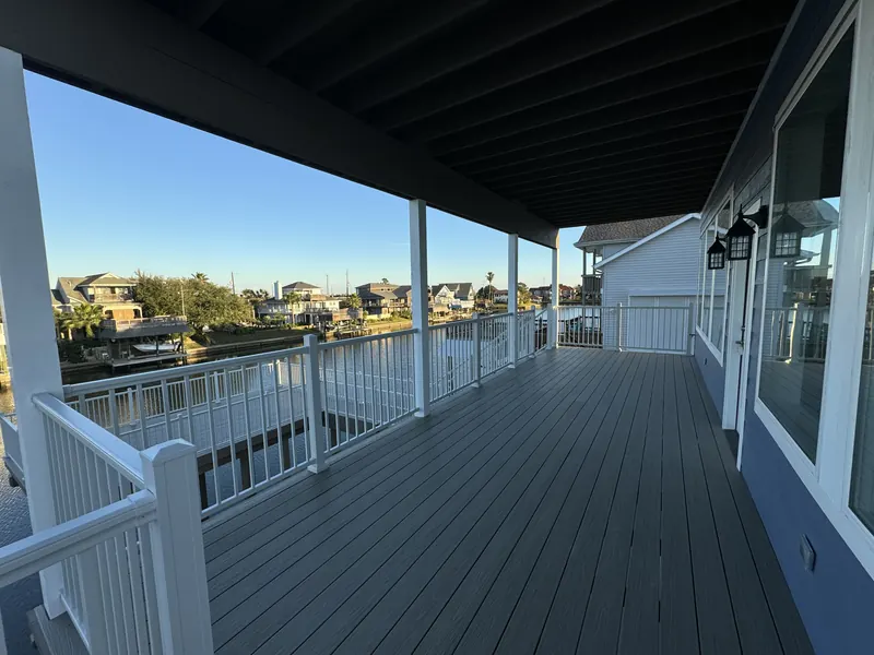 Covered wraparound deck at Galleon with white railing, composite decking, and canal views down the length of the house