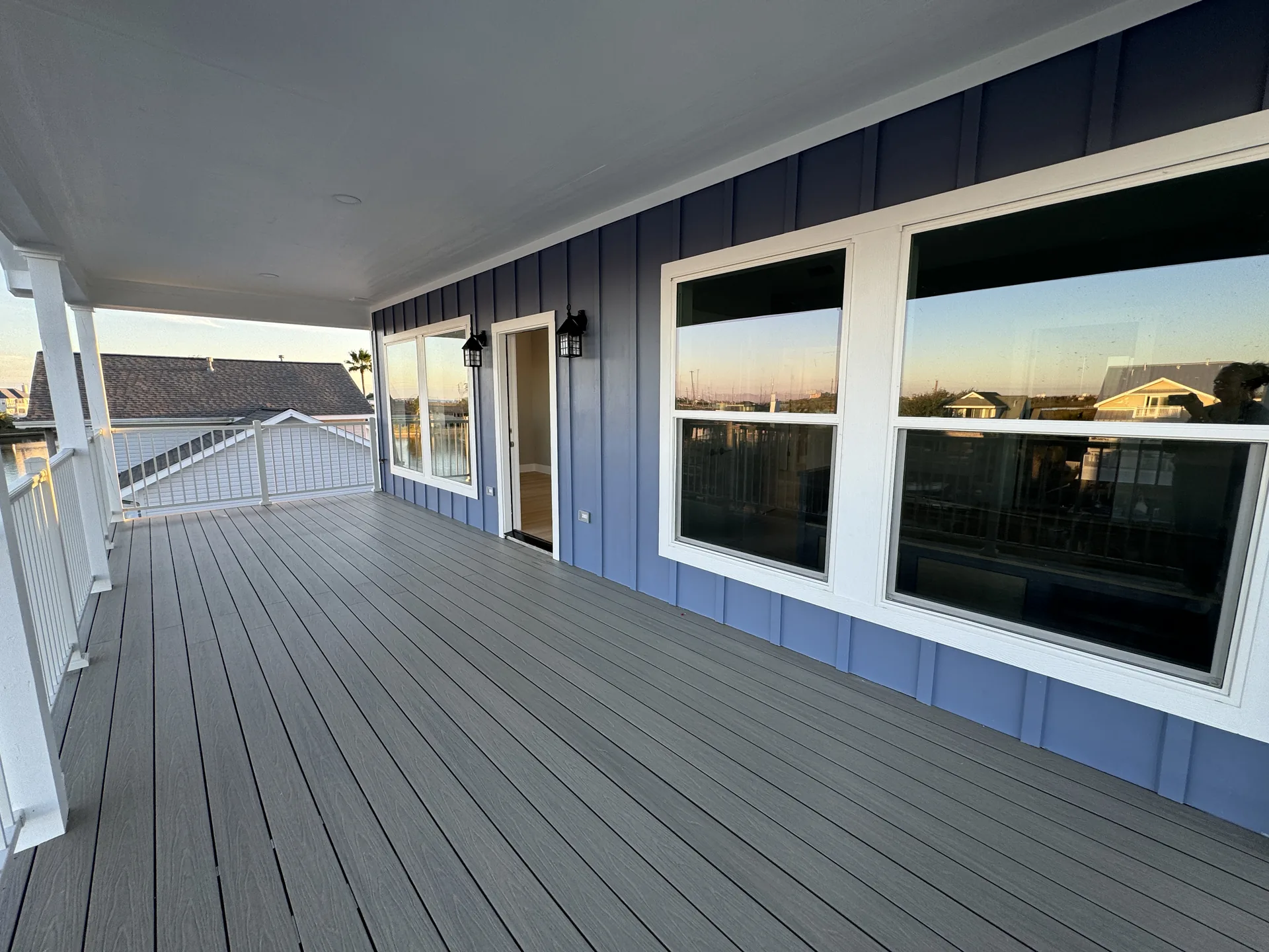 Wide view along the Galleon deck showing the blue lap siding, oversized windows, and shaded outdoor living space