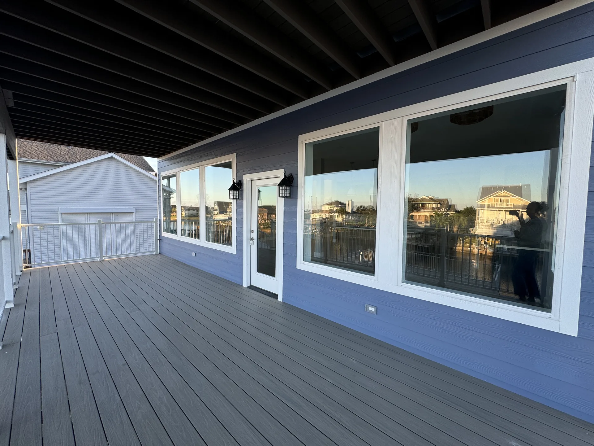 Waterside elevation of Galleon with navy blue siding, white trim, and a run of picture windows facing the canal
