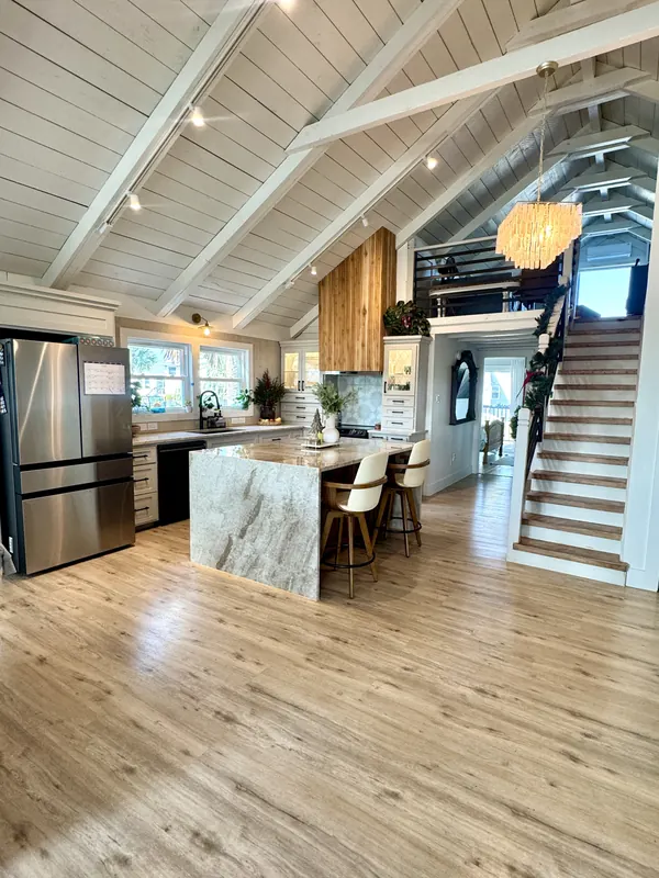 Kitchen and great room of the Jamaica Beach addition with a quartz island, vaulted ceiling, and open stair to the loft
