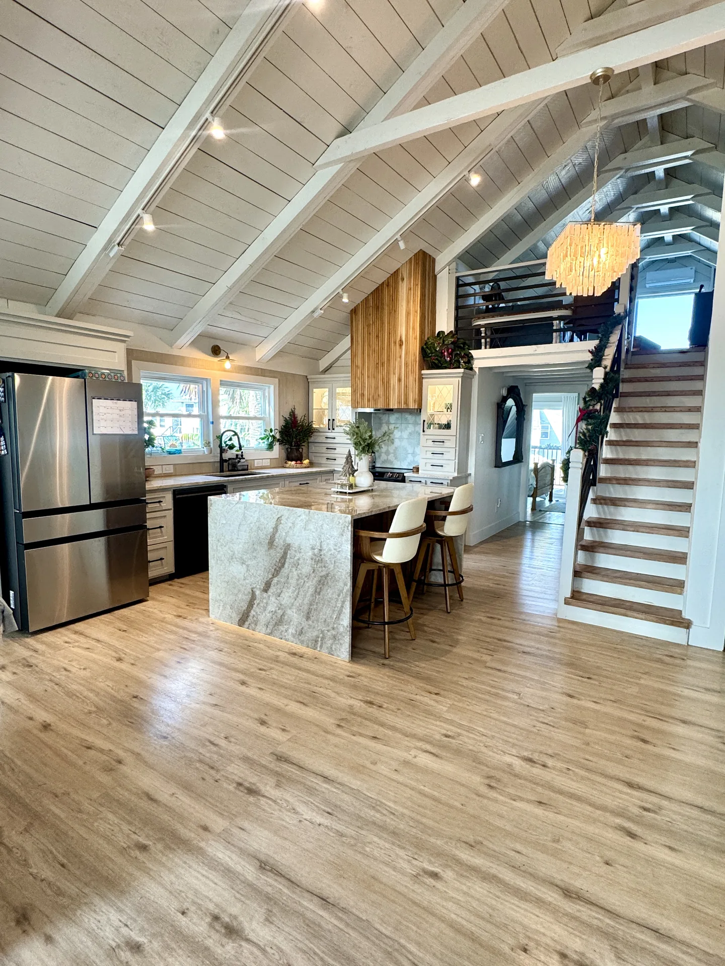 Kitchen and great room of the Jamaica Beach addition with a quartz island, vaulted ceiling, and open stair to the loft