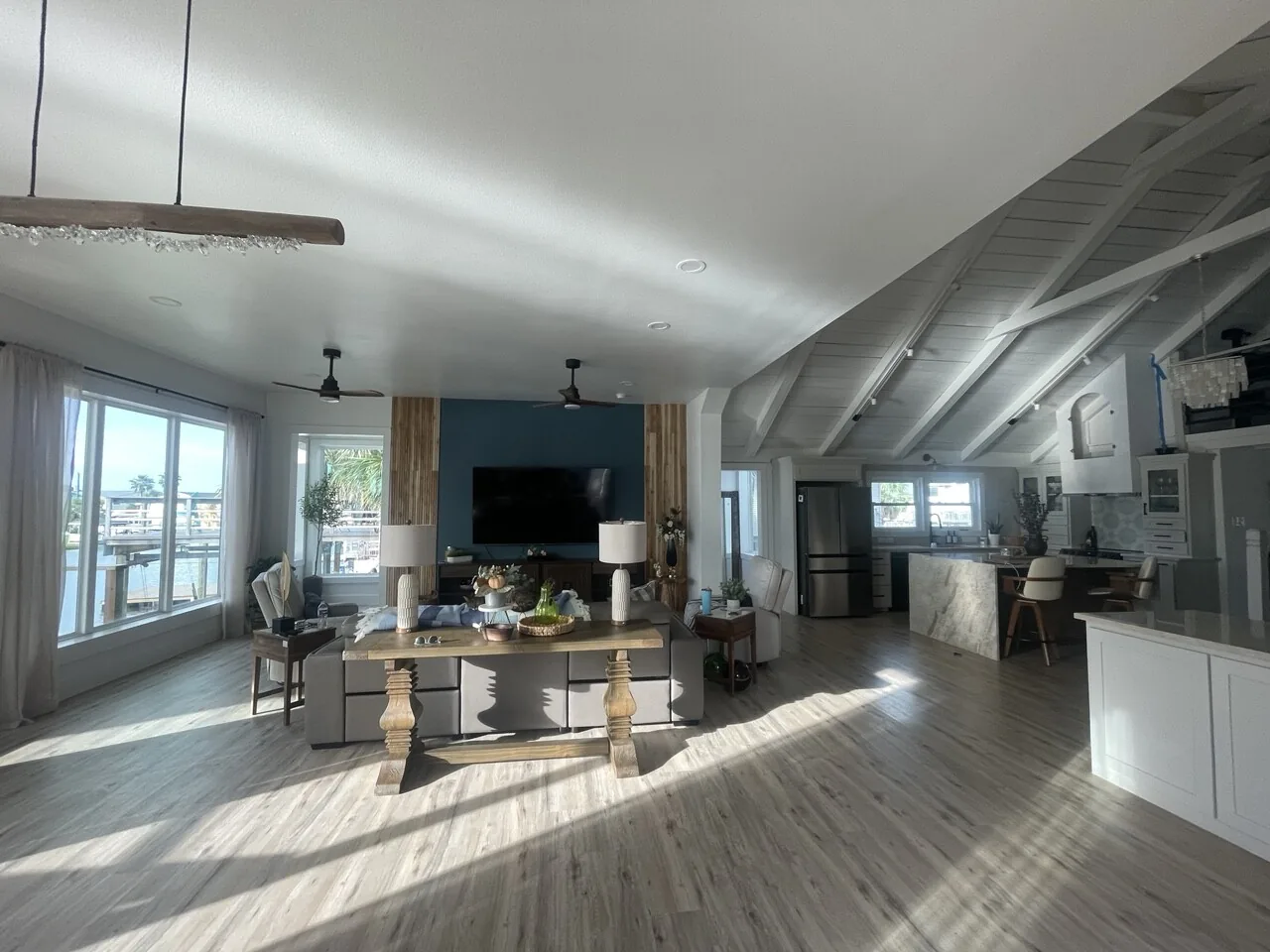 After: wide view of the renovated Jamaica Beach great room, vaulted in whitewashed shiplap with the beams painted out