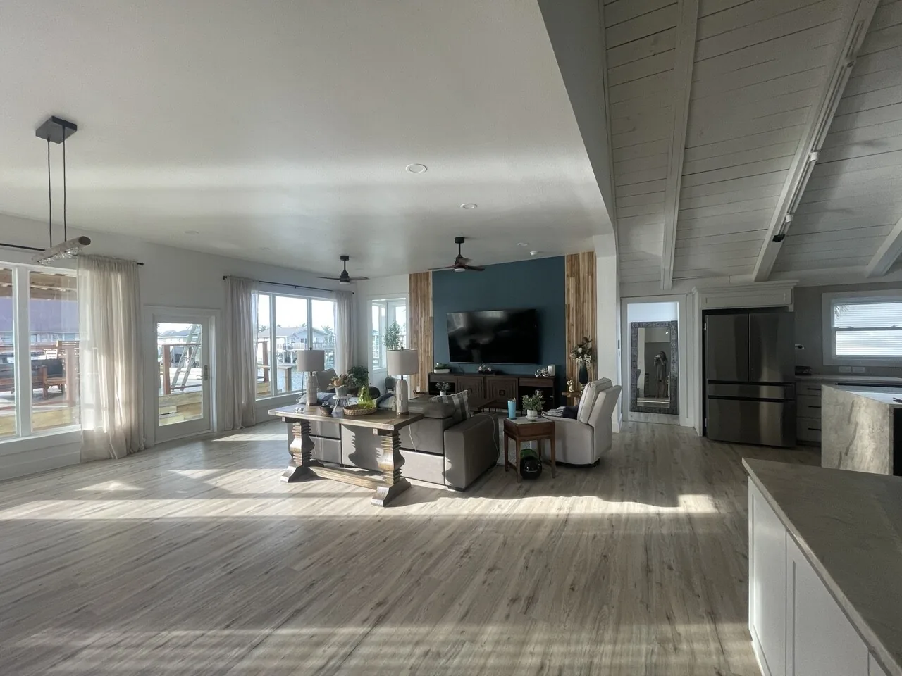After: renovated great room with open dining and living space beneath the vaulted white ceiling