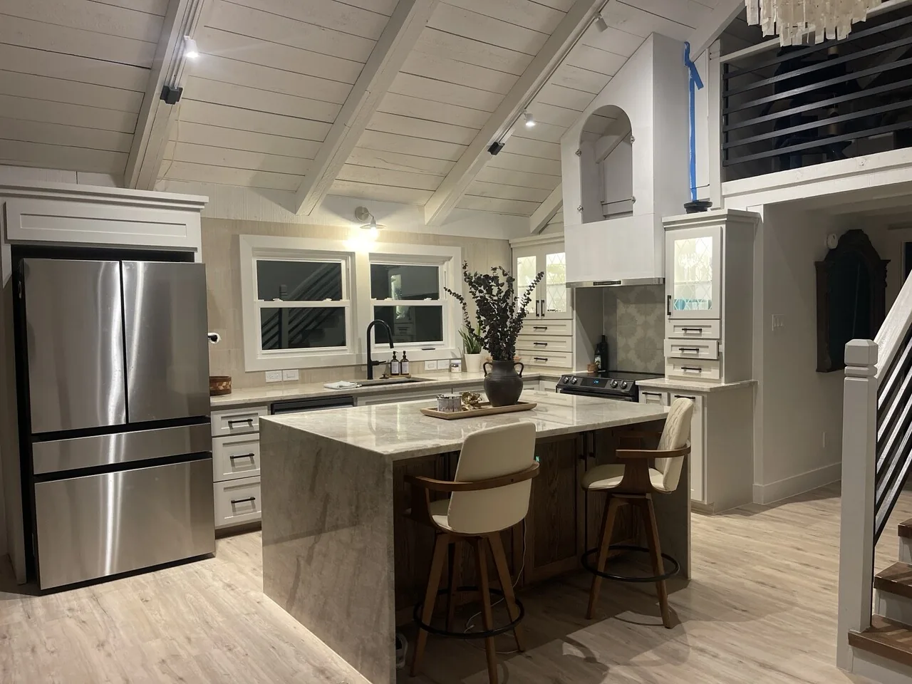 After: quartz waterfall island in the renovated Jamaica Beach kitchen with bar seating and stainless appliances