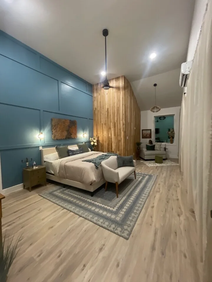 After: renovated bedroom with a full-height wood slat accent wall and modern pendant lighting