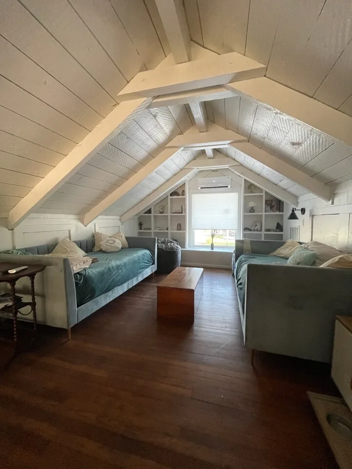After: loft sitting room under the renovated vaulted ceiling with white-painted beams and dark wood flooring
