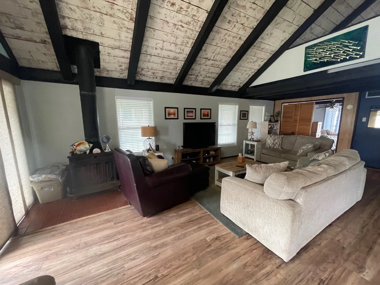 Before: original living room with dark A-frame beams, dated furnishings, and low light