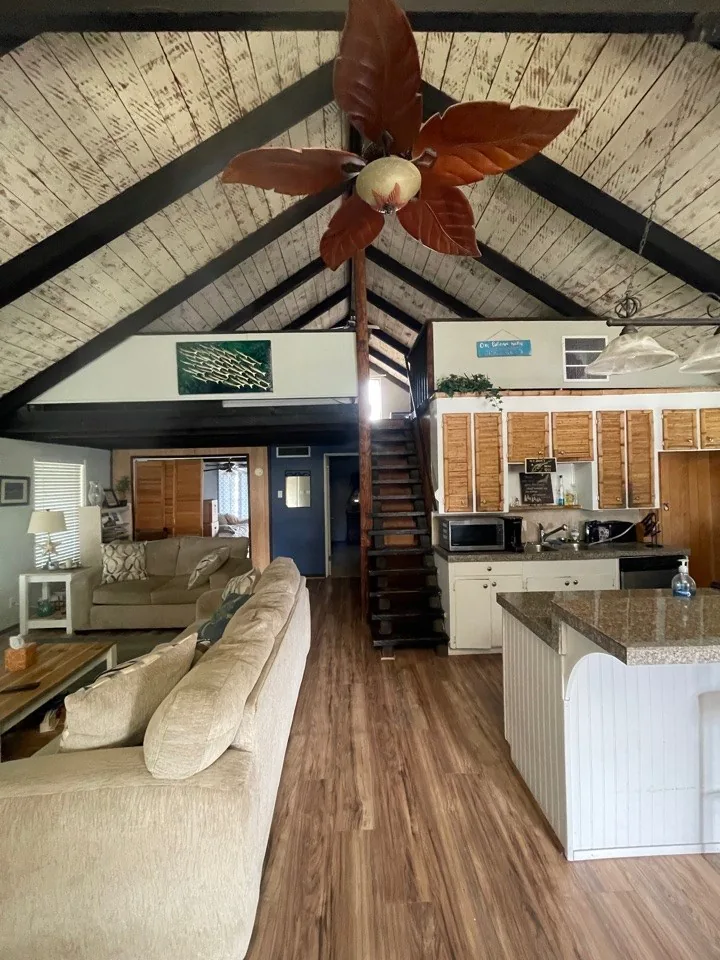 Before: original kitchen and living area under the dark stained A-frame ceiling