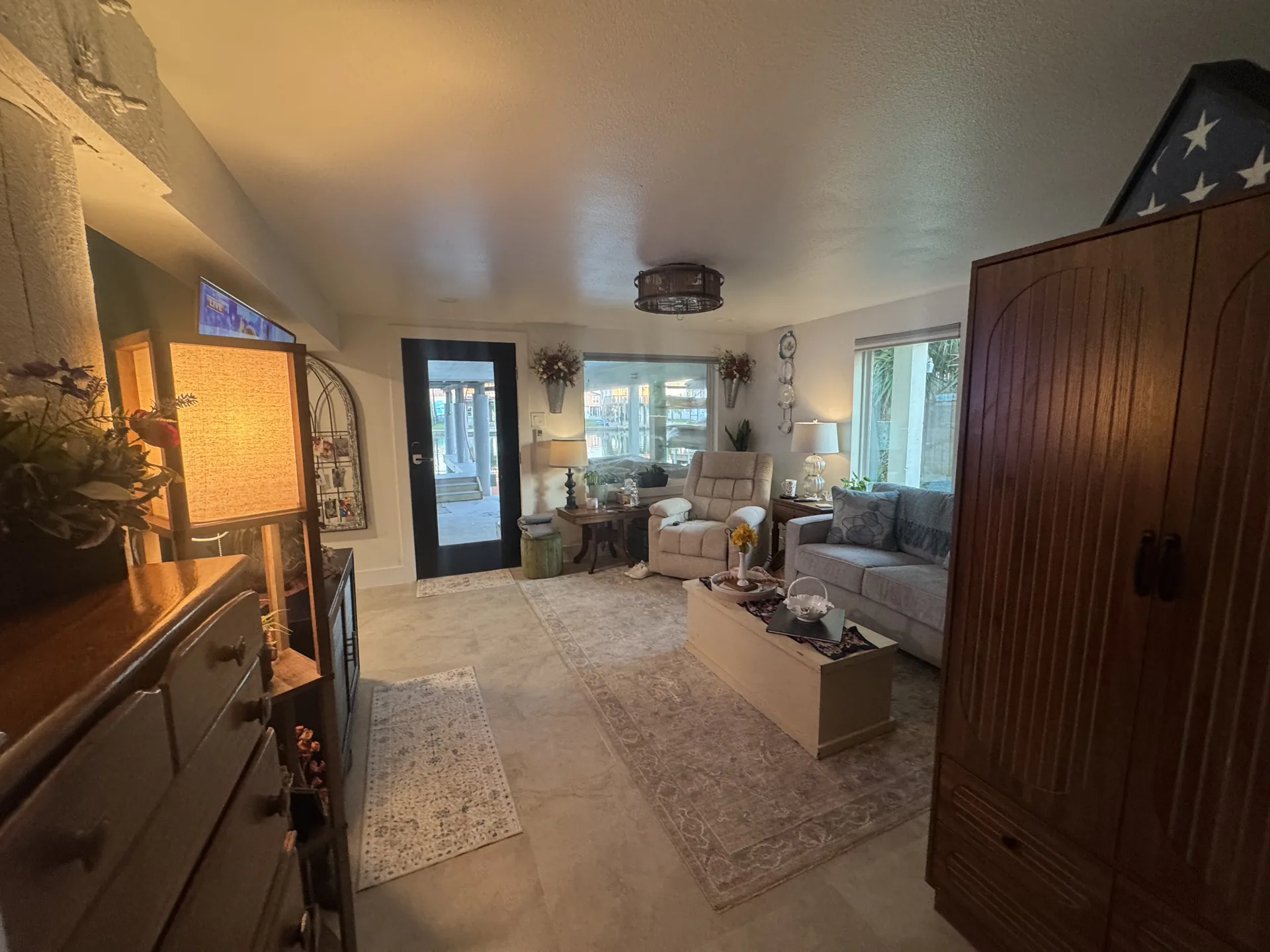 Living space and entry of the one bedroom conversion, with a tall wood armoire and open sightline to the seating area