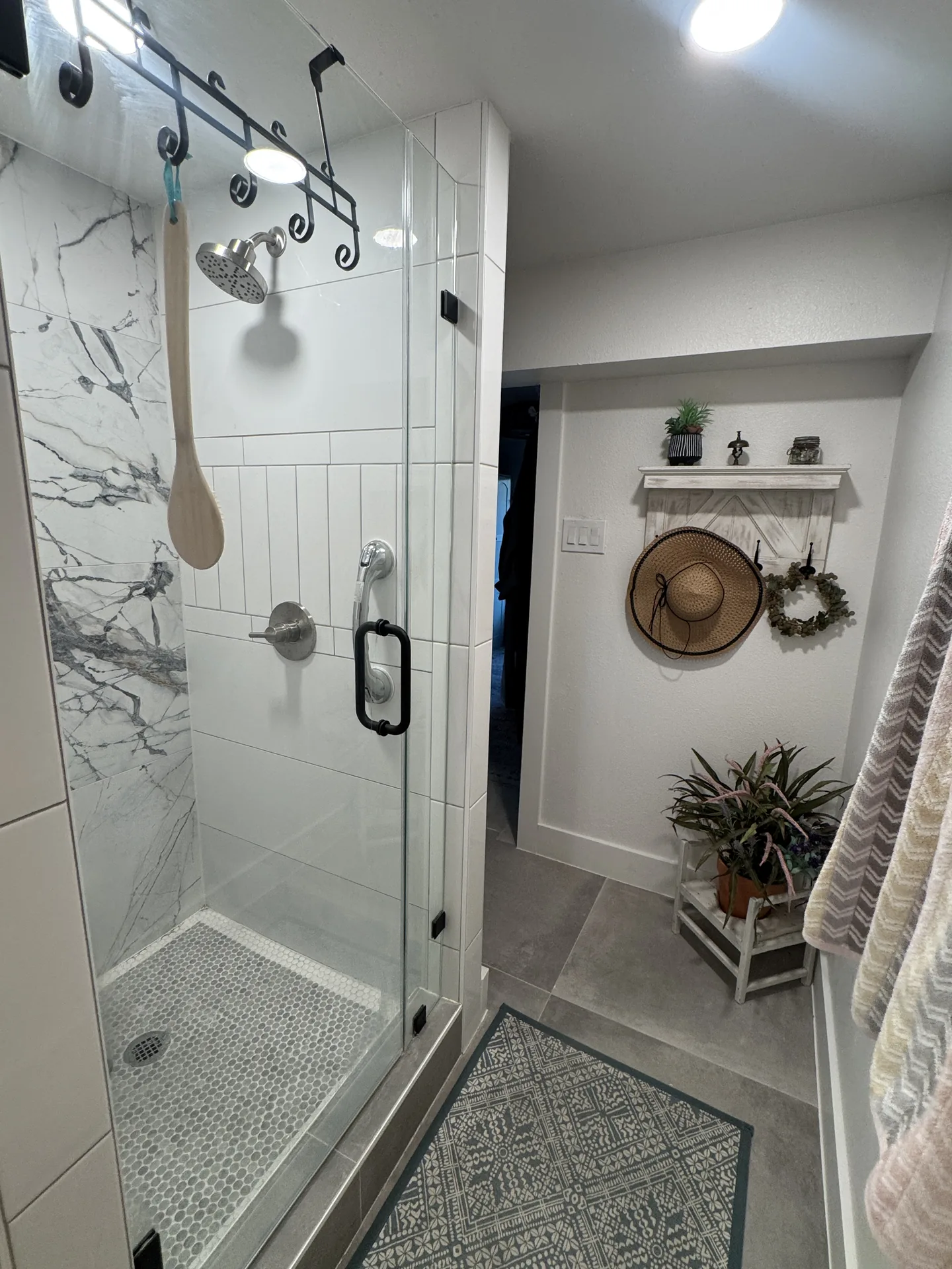 Marble-look walk-in shower with frameless glass enclosure in the renovated Galveston bath