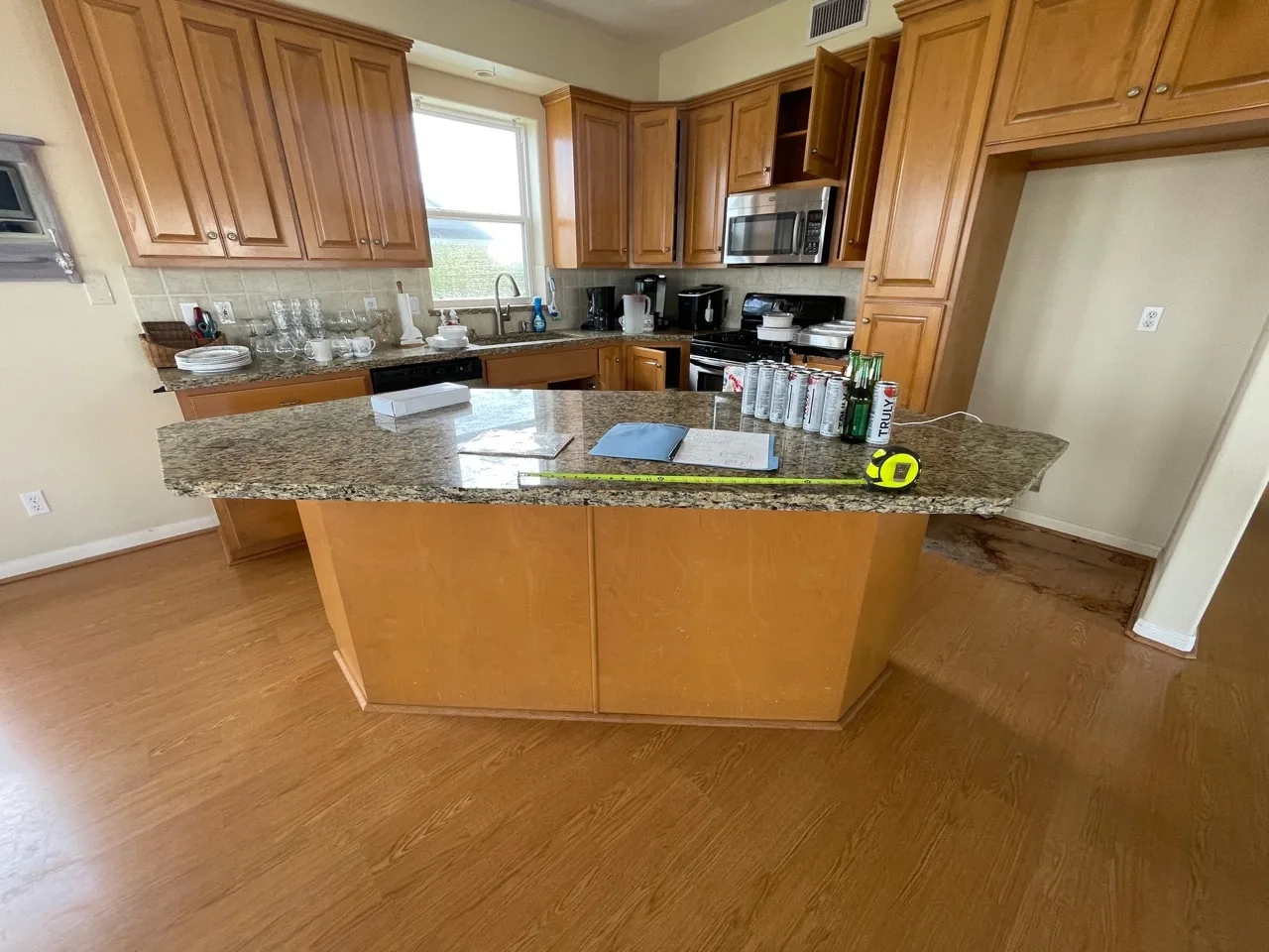 Before: original kitchen at the Tern house with oak cabinetry, granite counters, and a large angled peninsula