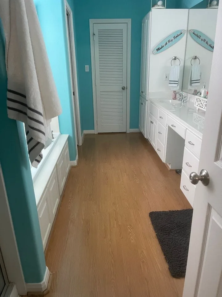 Before: original bath with teal walls, a white vanity run, and a dark floor mat