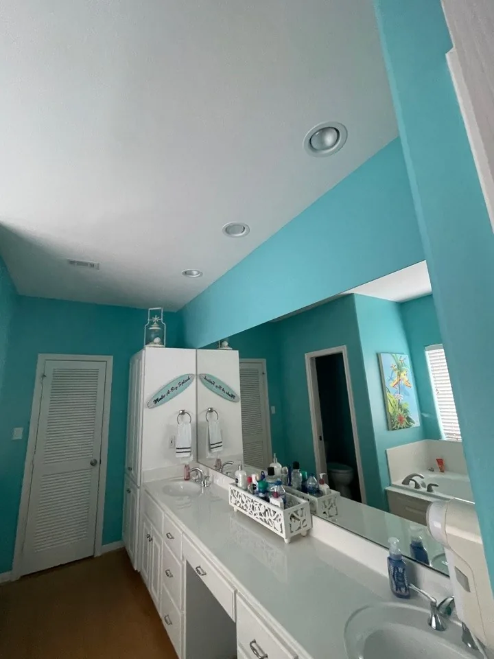 Before: original bath vanity with teal walls, mirrored wall cabinet, and dated lighting