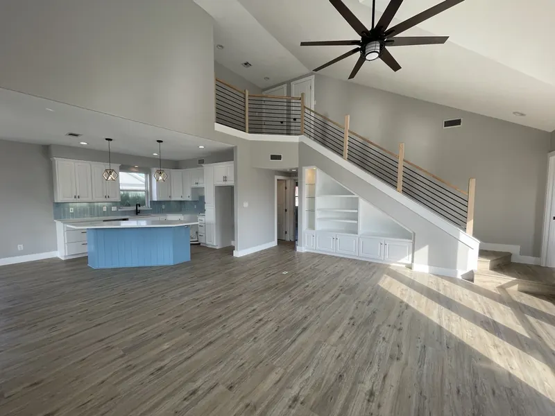 After: renovated two-story great room at Tern with the new kitchen, blue island, and open stair beyond