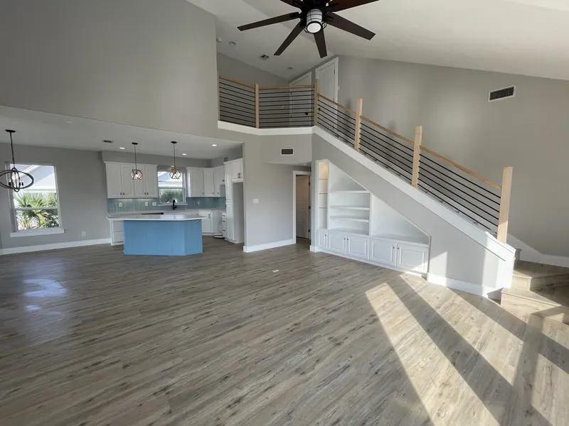 After: great room at the Tern renovation with vaulted ceiling, oversized fan, and new wood-look flooring