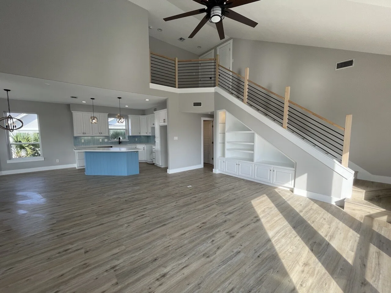 After: great room at the Tern renovation with vaulted ceiling, oversized fan, and new wood-look flooring