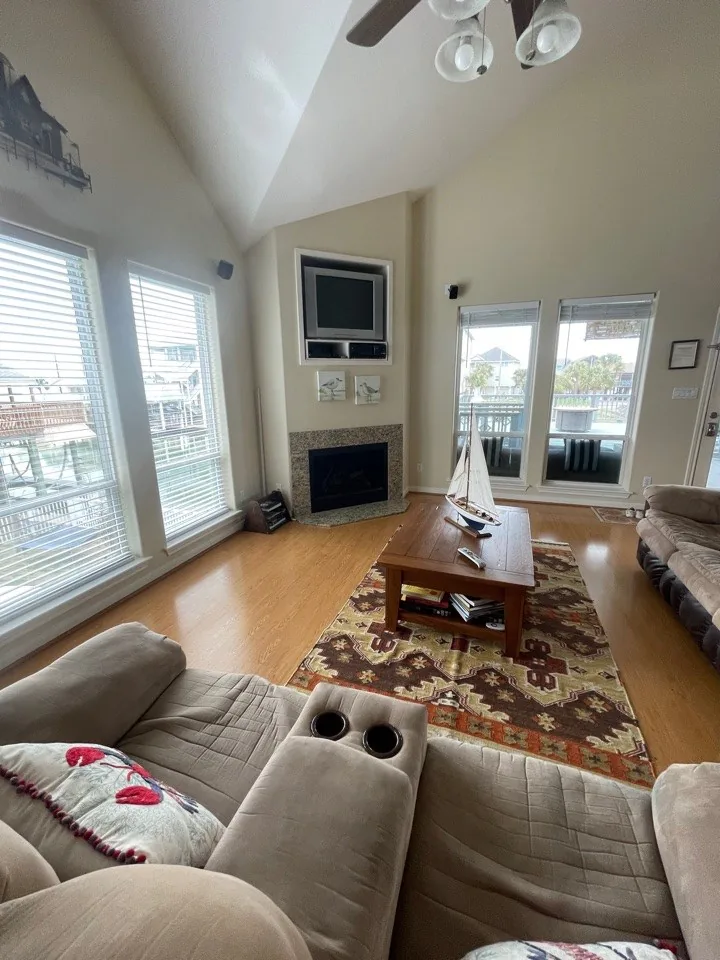 Before: original living area with vaulted ceiling, corner fireplace, and dated furnishings