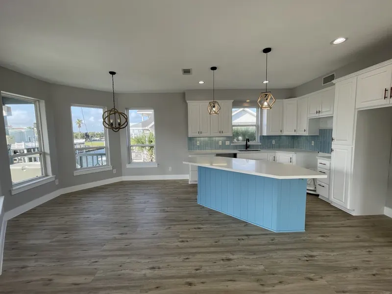 After: renovated kitchen at Tern with white cabinetry, blue island, and glass tile backsplash