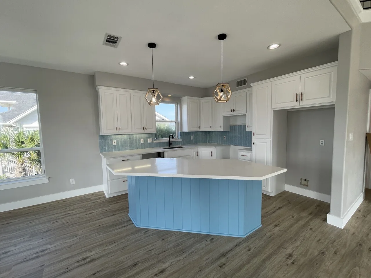 After: Tern kitchen island in soft blue with quartz counter and pendant lighting above