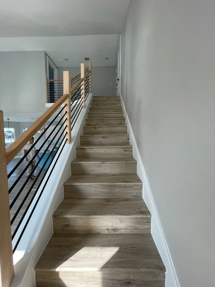 After: new staircase at Tern with horizontal metal railing, wood cap, and wood-look treads