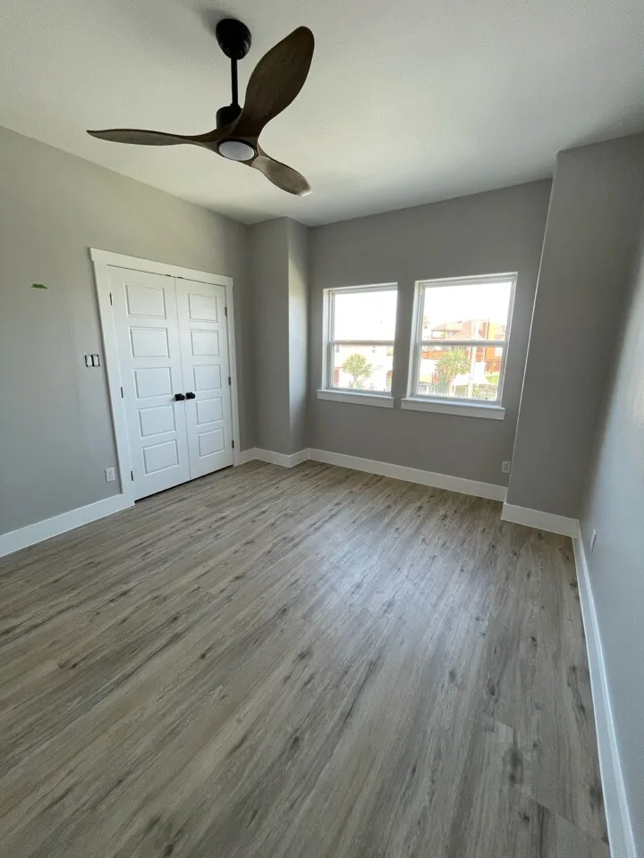After: renovated bedroom at Tern with fresh paint, a modern ceiling fan, and new wood-look flooring