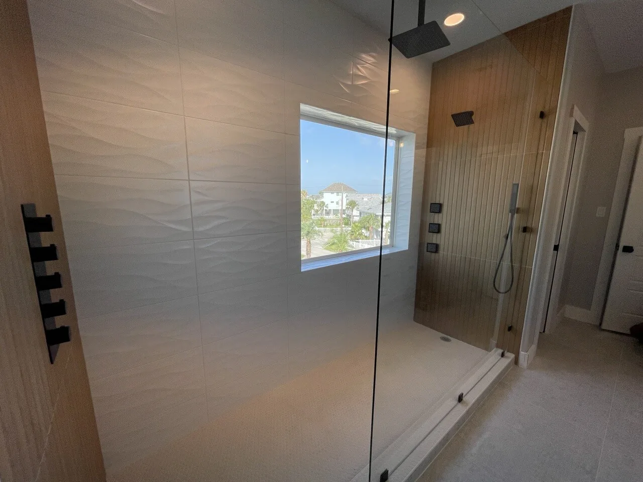 After: renovated walk-in shower at Tern with large-format wall tile, black fixtures, and a window