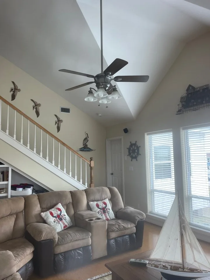 Before: original living room and staircase with carpeted treads and a colonial spindle railing