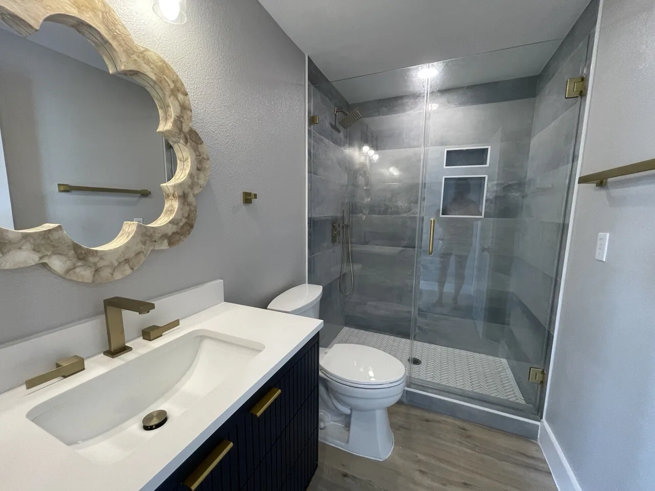 After: renovated bath at Tern with a navy vanity, gold fixtures, and an ornate gold-framed mirror
