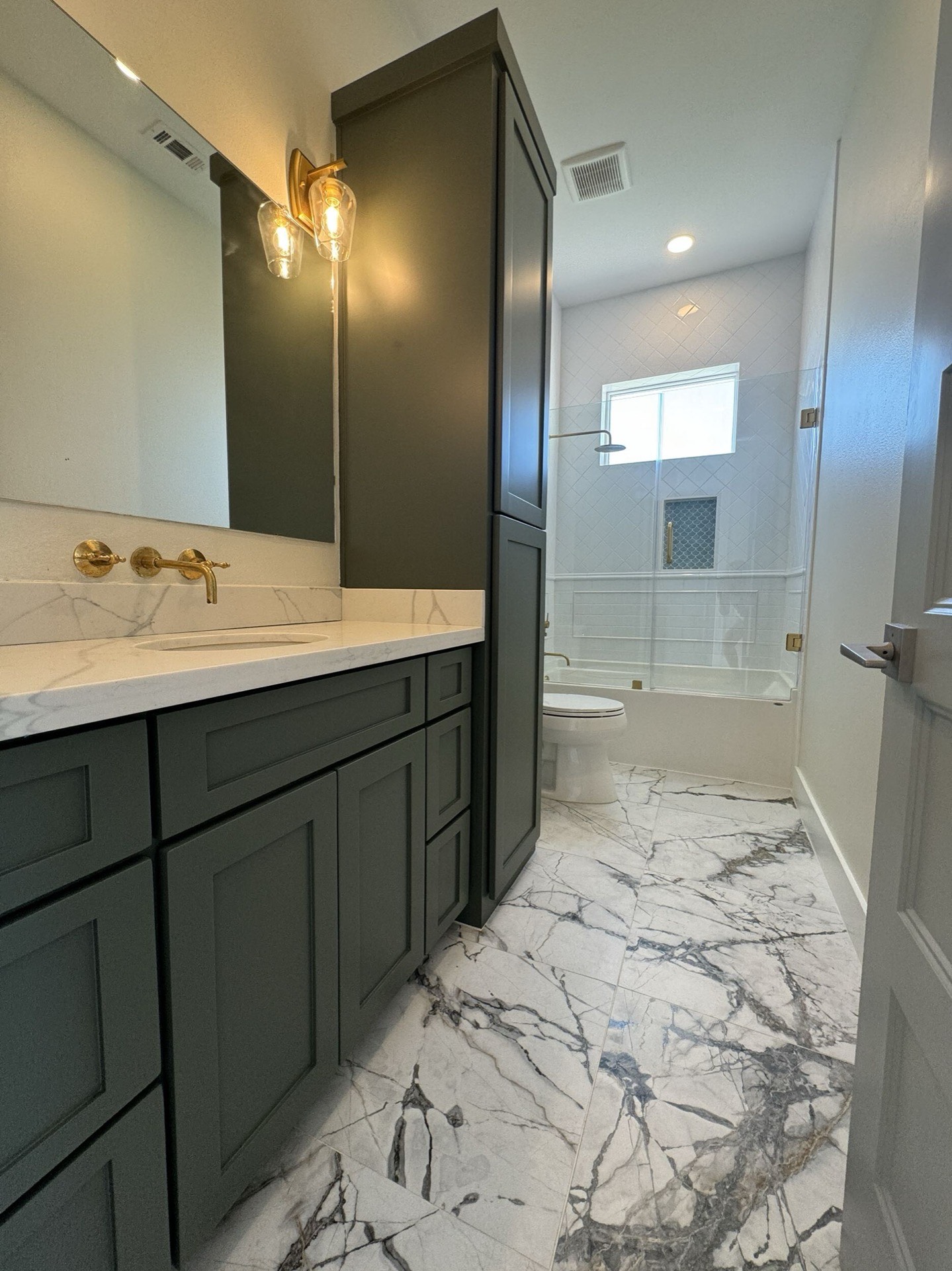 Kitchen island with sage green base, white countertop, pendant lighting, and views through to the living area and bay windows beyond