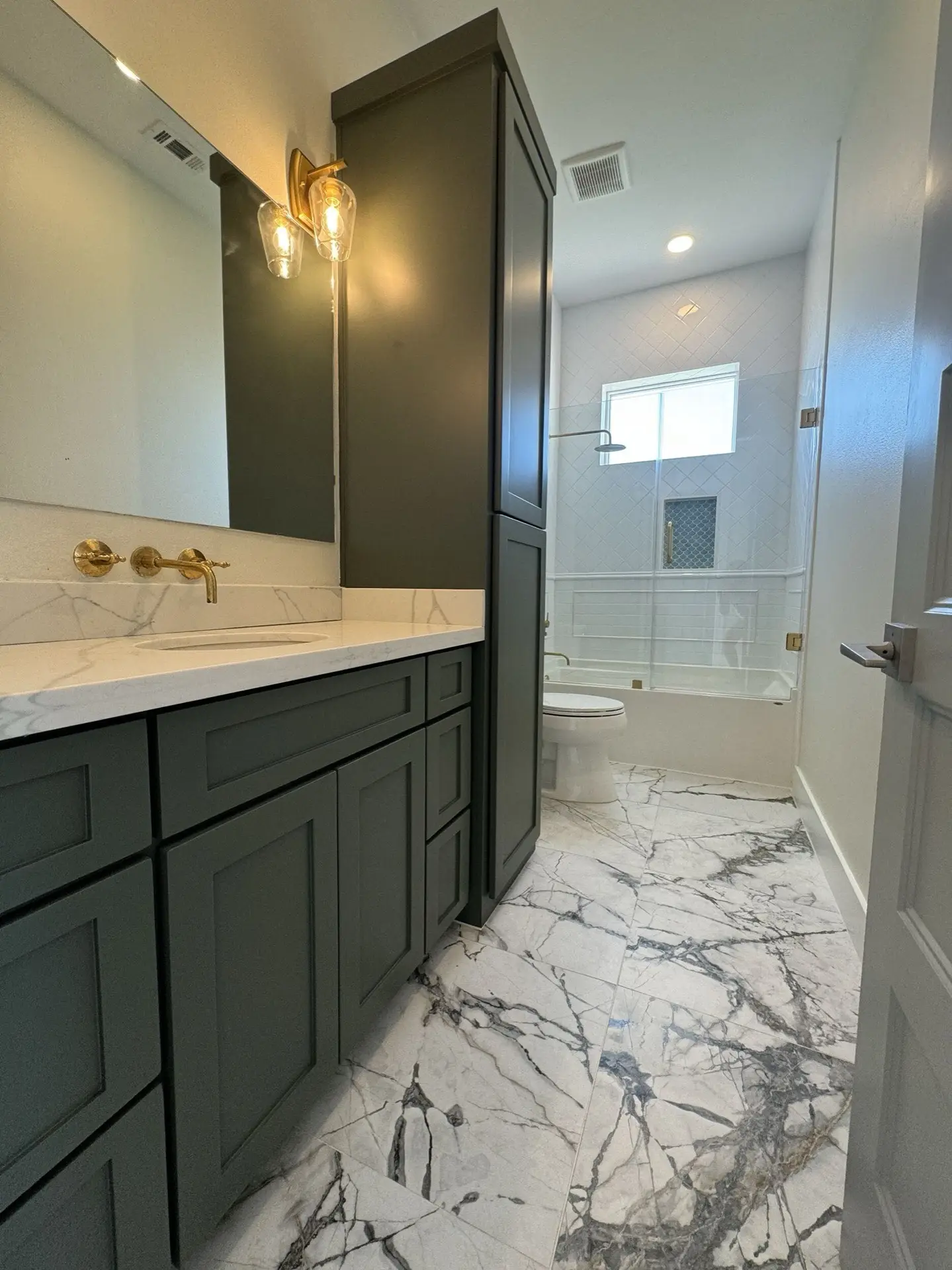 Kitchen island with sage green base, white countertop, pendant lighting, and views through to the living area and bay windows beyond