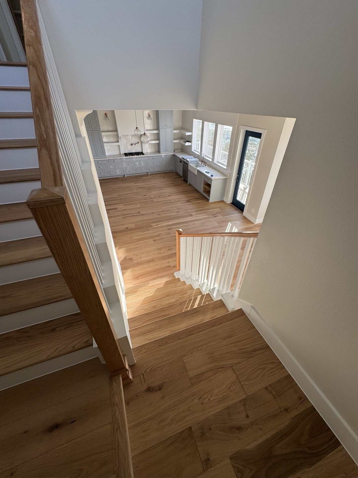 View from the living area through to the kitchen showing the open floor plan, consistent oak flooring, and crown molding throughout